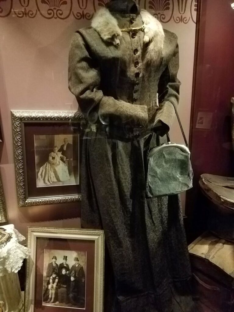 Historic Victorian women's dark dress with fur collar and handbag at Boot Hill Museum