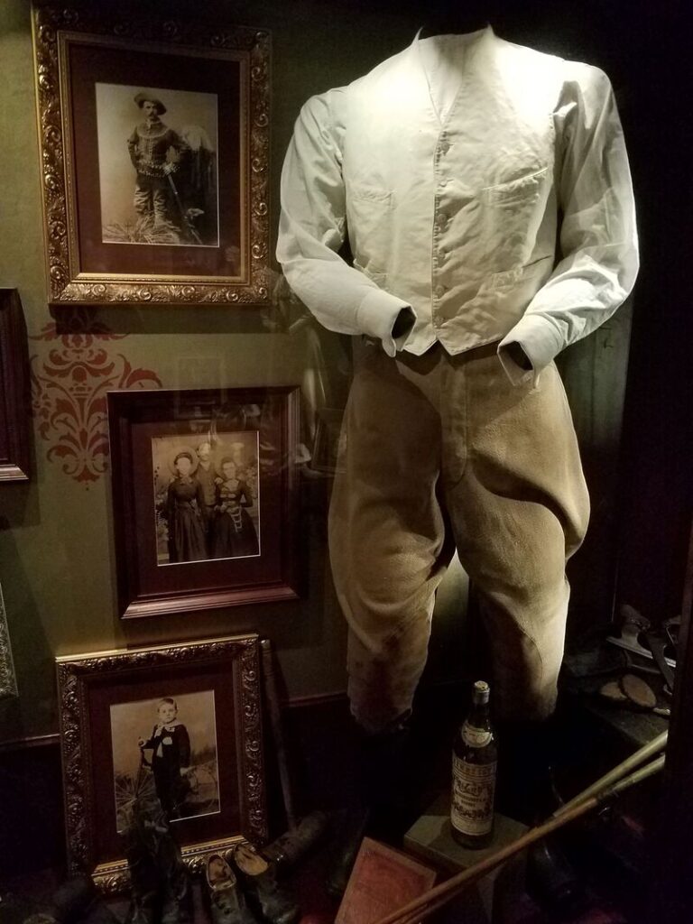 Historic men's everyday shirt and trousers displayed with period photographs at Boot Hill Museum