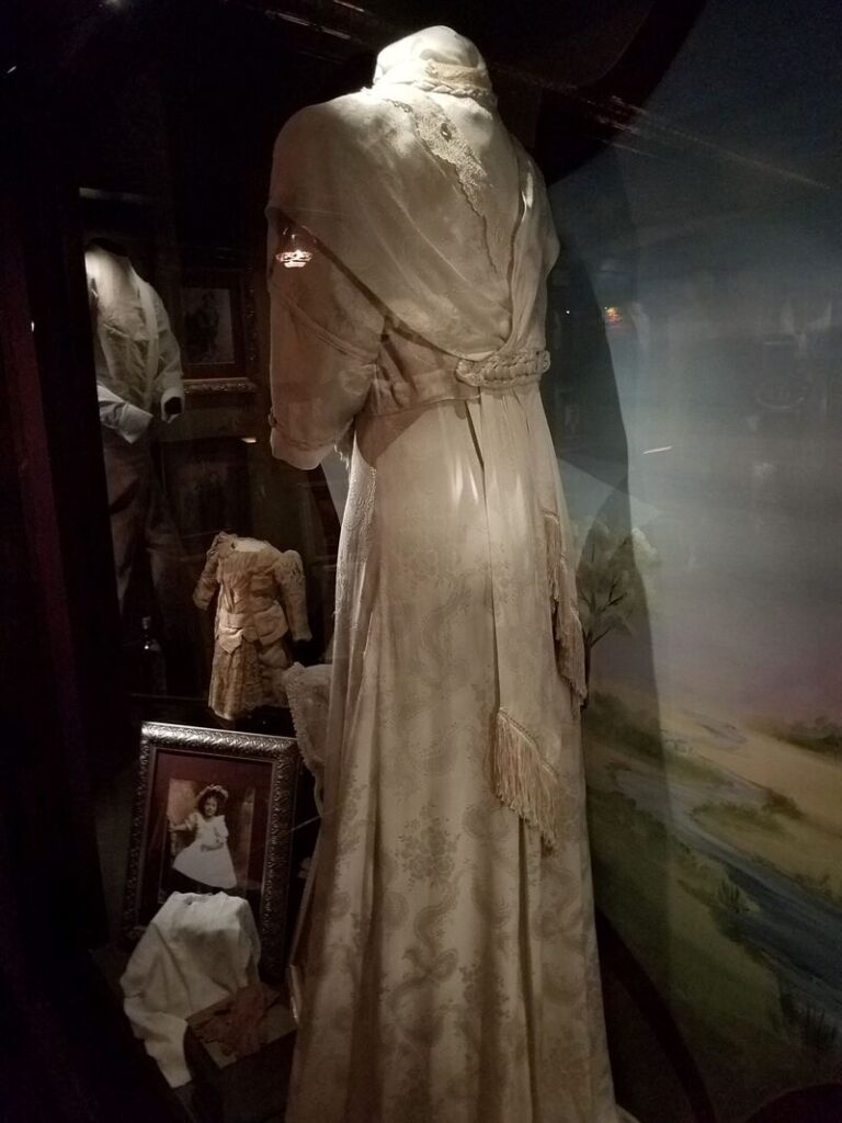 Detailed back view of historic dress with draped waist and patterned skirt at Boot Hill Museum